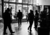 Job losses to hit manufacturing and retail as growth slows and energy costs rise Silhouetted figures walk through a busy indoor lobby in a black and white composition.