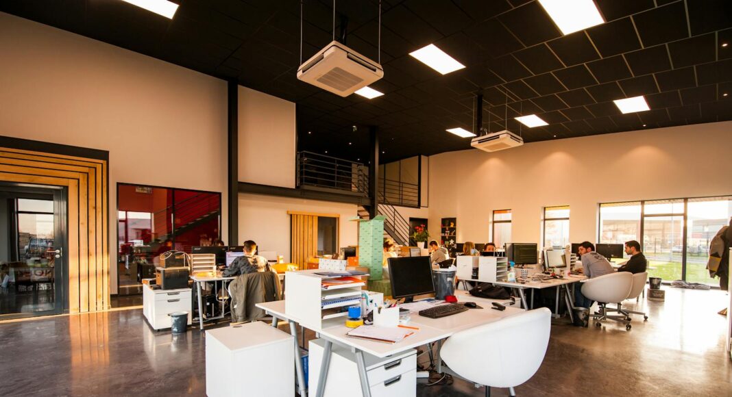 A spacious and modern open-plan office with natural lighting and employees working at desks.