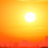 A city skyline silhouetted against a vivid, orange sunset sky.