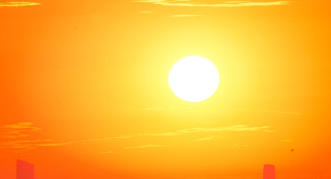 A city skyline silhouetted against a vivid, orange sunset sky.
