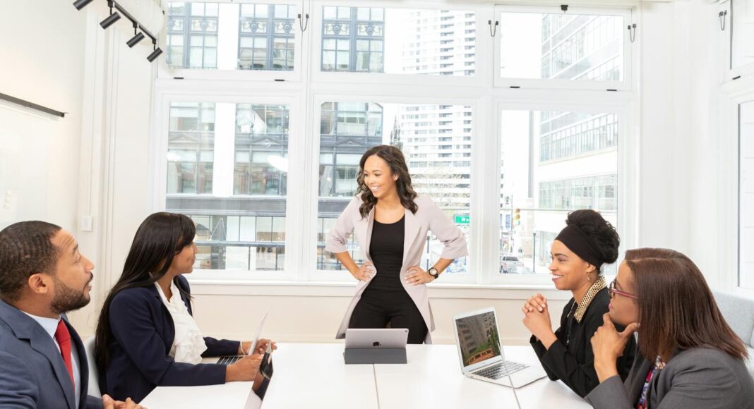A diverse team engaged in a business meeting with laptops in a modern office setting.
