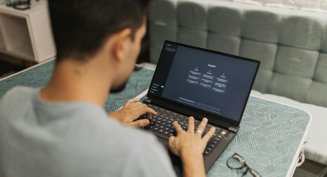 A man working on a laptop displaying ChatGPT's interface in an indoor setting.