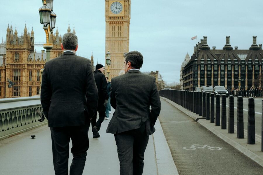 Two businessmen in suits walking on Westminster Bridge with Big Ben in the background, London.