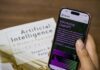 Employers urged to rethink race for chief AI officers Close-up of a smartphone displaying ChatGPT app held over AI textbook.