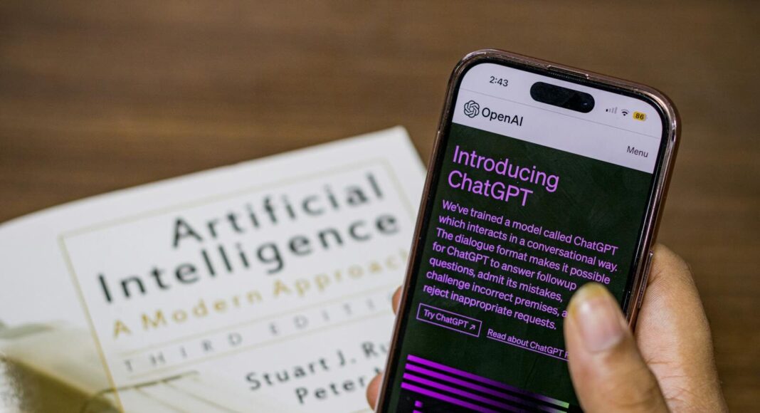Close-up of a smartphone displaying ChatGPT app held over AI textbook.
