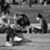 Three young adults sitting on a bench in a vibrant urban setting.
