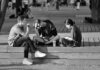 Targeted hiring grants beat tax cuts in tackling youth jobs crisis, report says Three young adults sitting on a bench in a vibrant urban setting.
