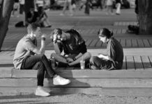 Targeted hiring grants beat tax cuts in tackling youth jobs crisis, report says Three young adults sitting on a bench in a vibrant urban setting.