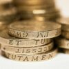 Close-up of stacked British pound coins with engraved text, representing wealth and finance.