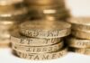 State pension age begins rise to 67 as payments increase Close-up of stacked British pound coins with engraved text, representing wealth and finance.