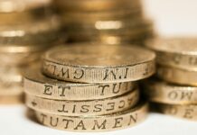 State pension age begins rise to 67 as payments increase Close-up of stacked British pound coins with engraved text, representing wealth and finance.