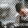 A man working behind a partly shieled glass screen.