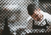 Recruitment firms caught up in rise in illegal working penalties A man working behind a partly shieled glass screen.