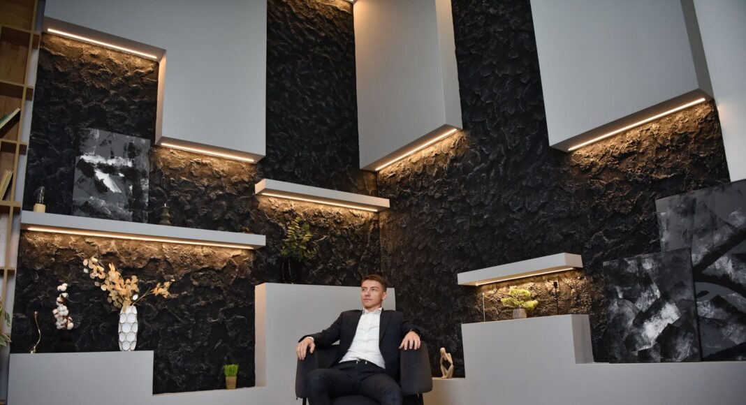 Photo by Andrii Sabadash A businessman in a suit sitting confidently in a modern office setting.