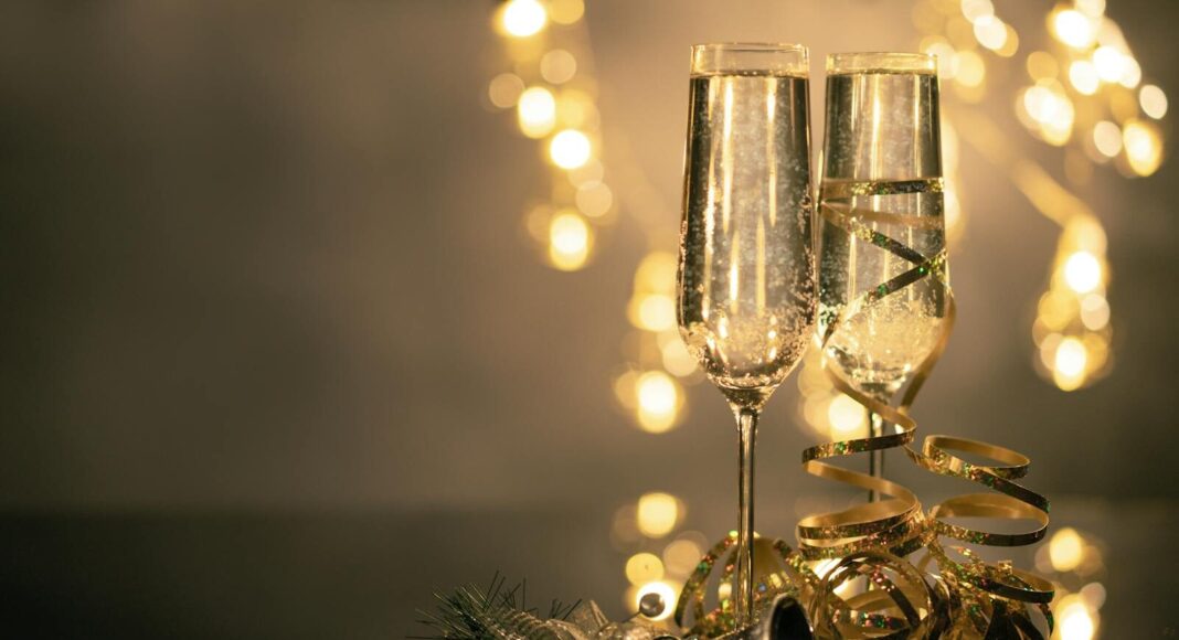 Champagne glasses with ribbons against festive lights.