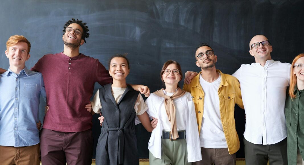 Photo by fauxels A diverse group of colleagues joyfully embracing in an office setting, showcasing team spirit.