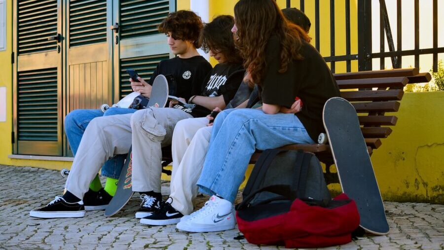 a group of people sitting on a bench with their laptops