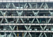 Employers plan smaller pay rises for 2027 despite inflation uncertainty Office building facade with glass windows.