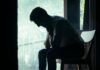 Mental health ‘stigma’ still stops staff speaking to managers A man sits alone in a moody indoor setting, silhouetted against a bright window, deep in thought.