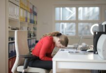 Burnout drives workers to value balance over pay A woman at her work desk rests her head on the table, suggesting burnout.