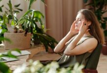 ‘Nearly half of employers lack formal wellbeing strategy’, raising concerns over support A woman relaxes, massaging her temples among indoor plants in a bright, sunlit room.