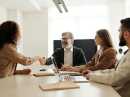 UK HR growth and DEI policies ‘costing firms £10bn a year’ People sit around an office table.