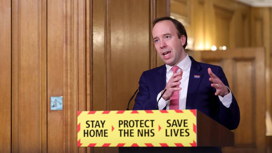 A man in a suit speaks at a podium with a sign reading 