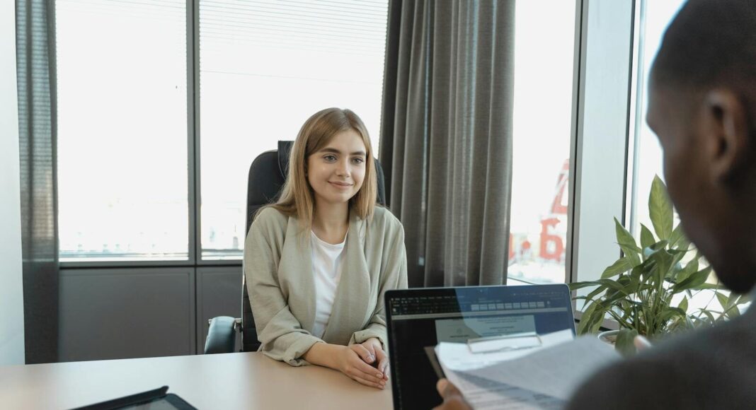 A young woman sitting confidently in a modern office for a job interview.