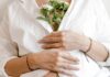 One in 10 women quit work after pregnancy loss, report finds A woman clutching flowers to her chest, signalling pregnancy loss.