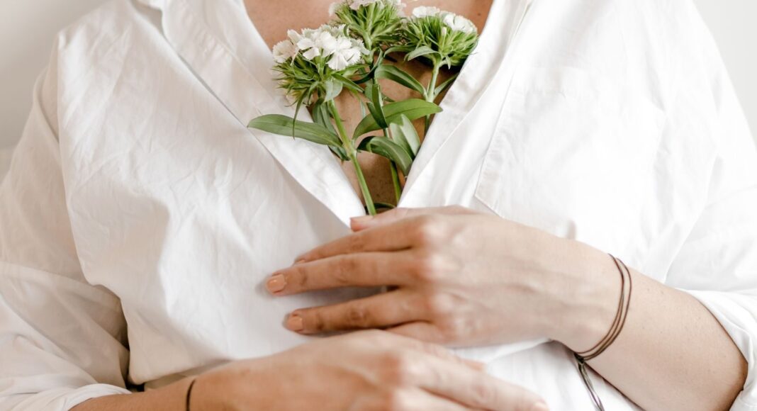 A woman clutching flowers to her chest, signalling pregnancy loss.