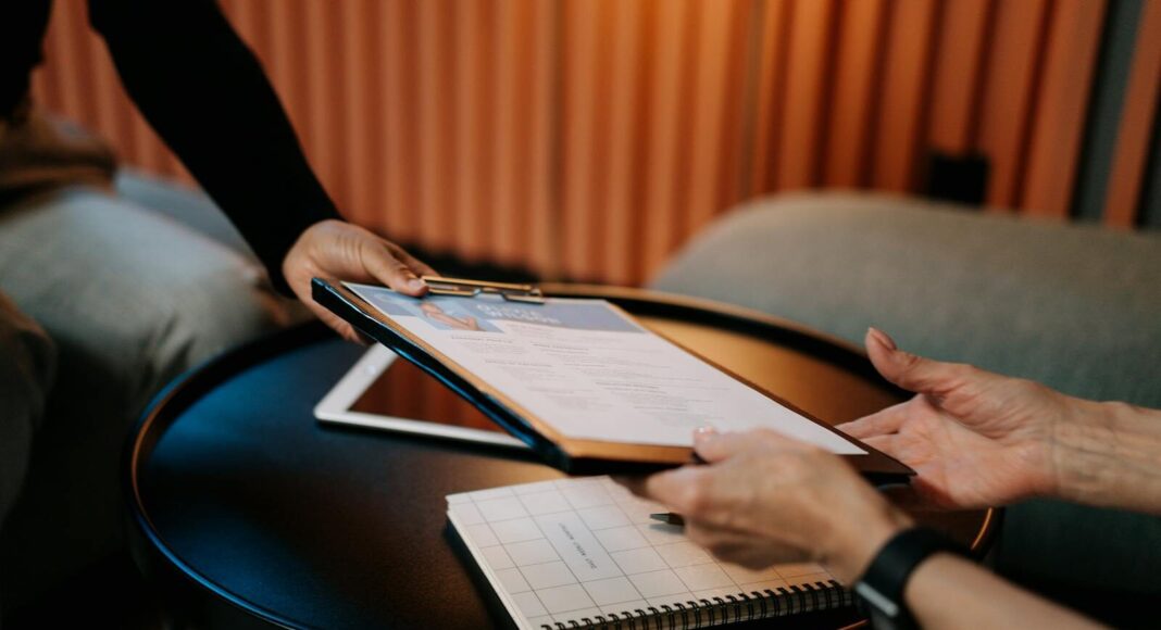 A person hands another person a form to fill out.