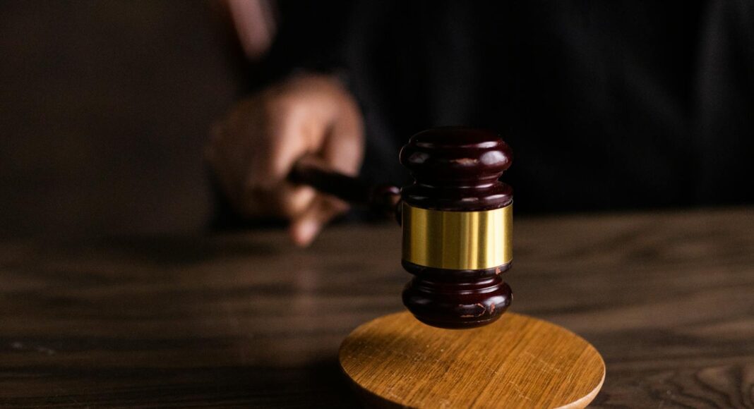 A gavel striking a block, symbolizing justice and legal authority in a courtroom setting.