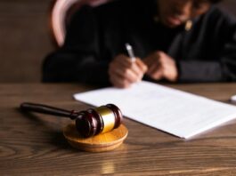 Employment tribunal roundup: Discipline rulings, pay disputes and settlement limits tested Judge signing documents at desk with focus on gavel, representing law and justice.
