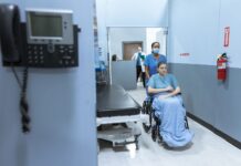 NHS badge review raises wider questions about political expression at work A nurse wheels a patient in a wheelchair down a hospital corridor, reflecting care and medical professionalism.