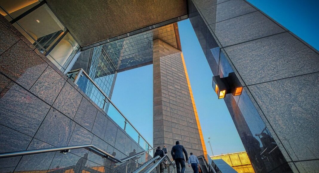People walking up the steps of an office building.