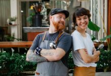 Optimism rises among UK workers but retirement fears persist A man and woman smiling at work.