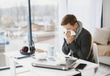 Sick pay overhaul set to reshape workplaces as reforms take hold Man sneezing at home desk, indicating remote work during illness.