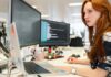 Government launches tech jobs drive to bring more women into the sector A young woman works at a desk with two monitors and a laptop.