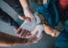 Workplace injuries hit 60,000 as safety gaps widen across UK Close-up of two people bandaging an injured hand outdoors, focusing on first aid care.