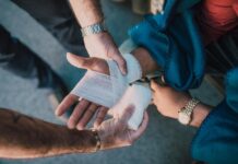 Workplace injuries hit 60,000 as safety gaps widen across UK Close-up of two people bandaging an injured hand outdoors, focusing on first aid care.