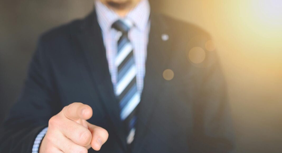 Confident businessman in a suit pointing forward, signifying leadership and focus.