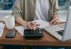 Three quarters of workers not saving enough for a moderate retirement, report warns A person using a calculator and laptop at a wooden desk.