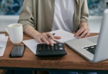 Three quarters of workers not saving enough for a moderate retirement, report warns A person using a calculator and laptop at a wooden desk.