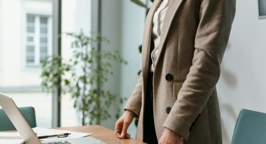 A professional businesswoman in a stylish office environment with a laptop and notes.