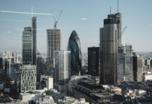 Pay growth hits five-year low as jobs market holds steady Various shaped modern skyscrapers with glass mirrored facades located in financial district of London against blue sky on sunny day