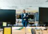 Brits dream of being their own boss, but still cling to the monthly pay cheque, survey reveals A businessman in a suit stands confidently in a modern office setting with crossed arms.