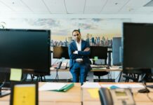 Brits dream of being their own boss, but still cling to the monthly pay cheque, survey reveals A businessman in a suit stands confidently in a modern office setting with crossed arms.