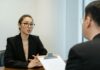 Law firm introduces AI interviews for graduates in hiring first A man interviews a young woman for a job.
