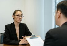 Law firm introduces AI interviews for graduates in hiring first A man interviews a young woman for a job.