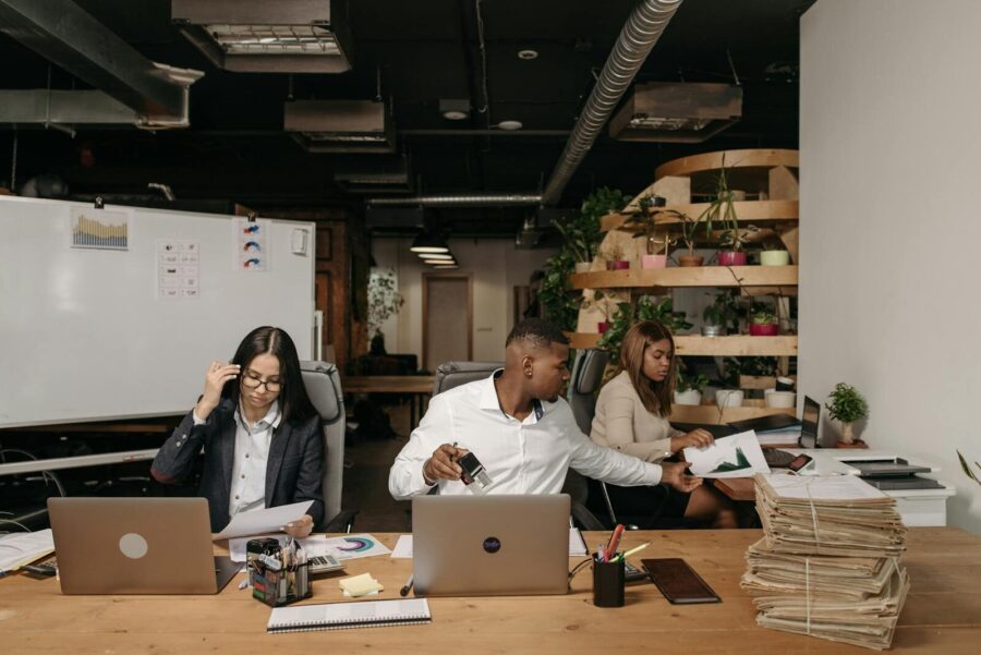 Photo by Pavel Danilyuk Diverse team collaborating in a modern office setting with laptops and documents.